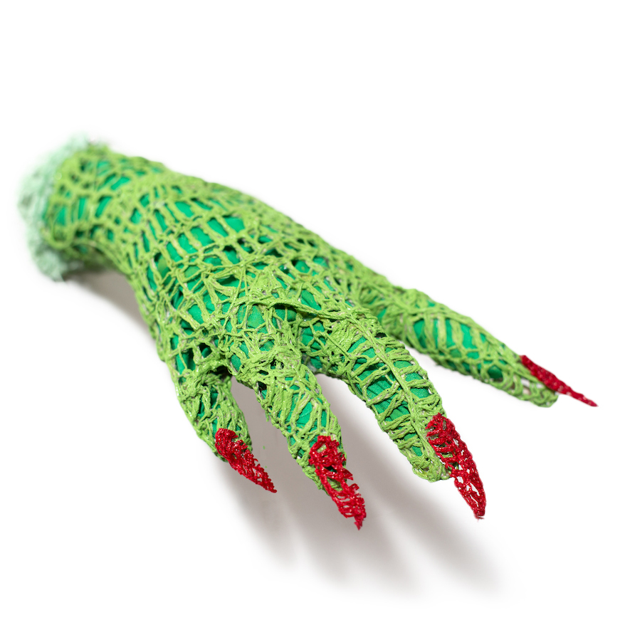 A sculpture of a hand in shades of bright green with red fingernails against a white background