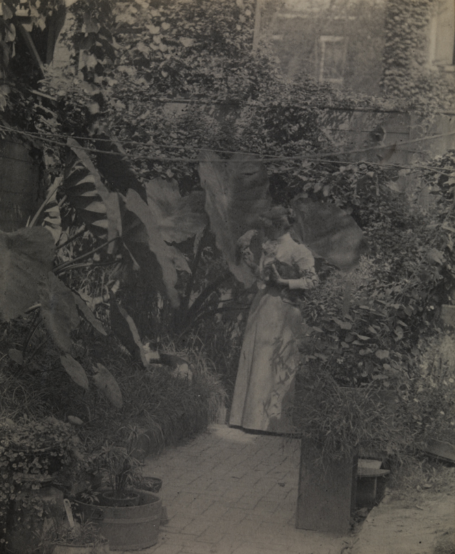 Susan Macdowell Eakins holding bird and cat in yard of the family home at 1729 Mount Vernon Street, Philadelphia