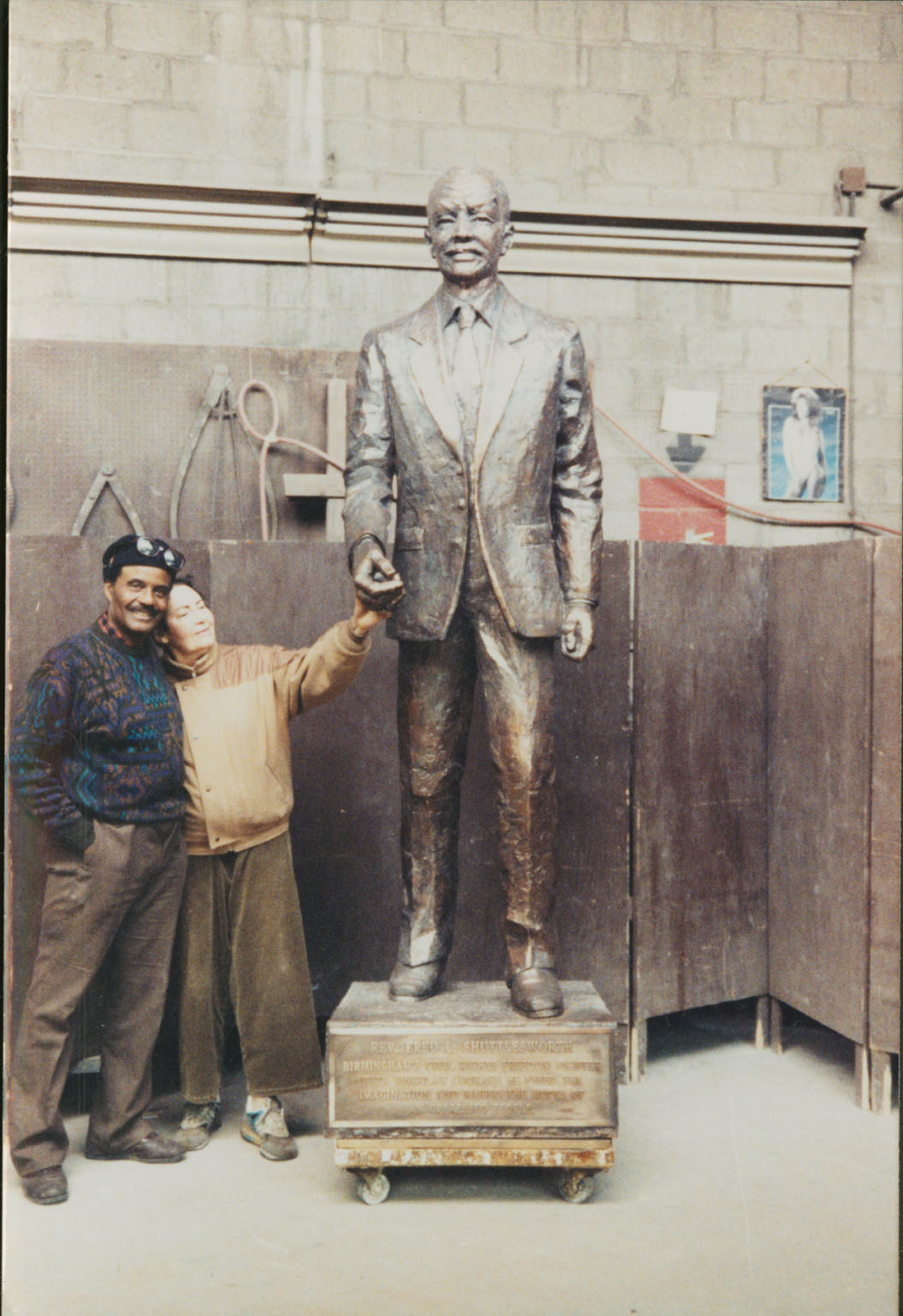 Two people standing next to a bronze sculpture.