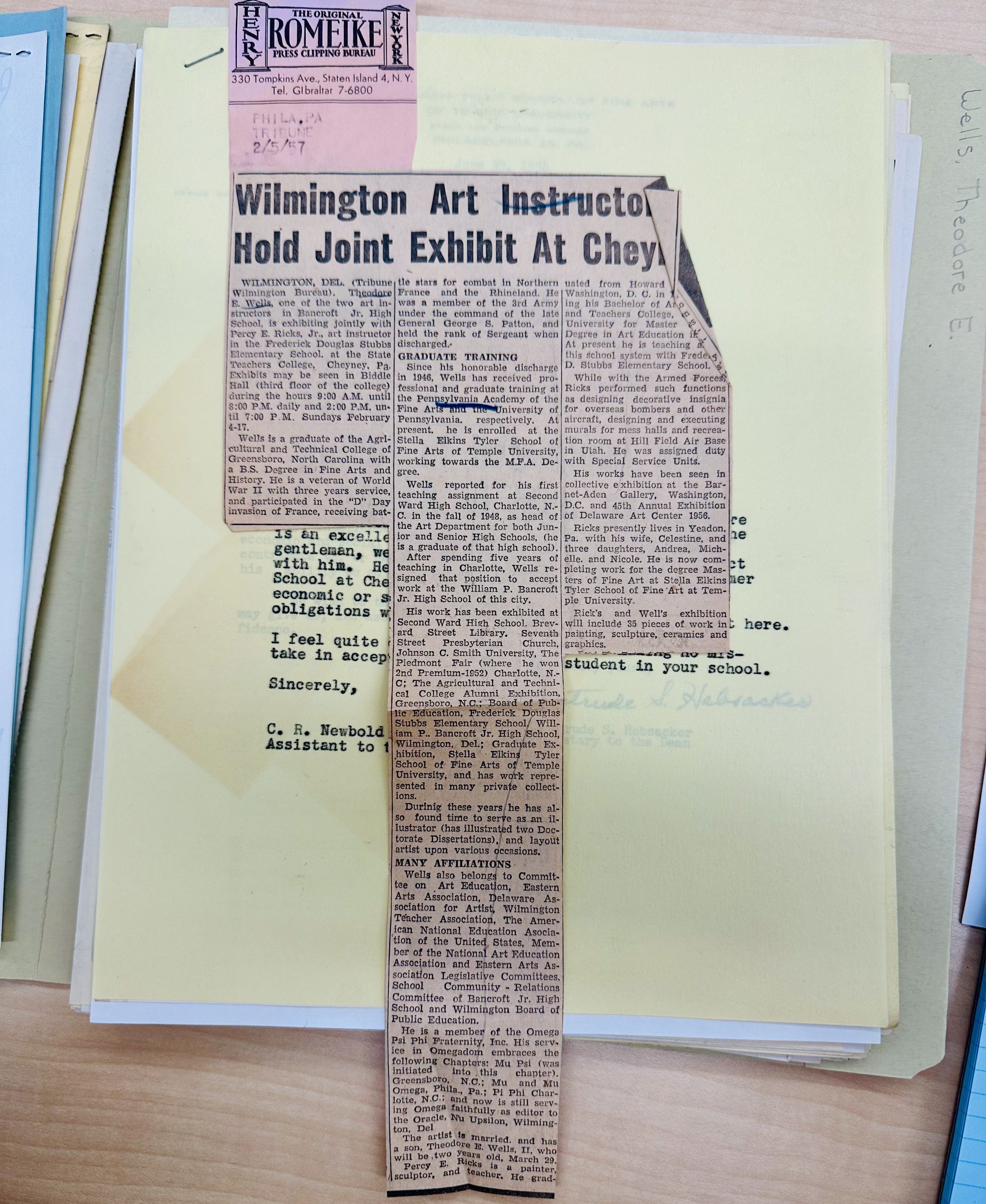 Newspaper article clipping atop a stack of archival files.