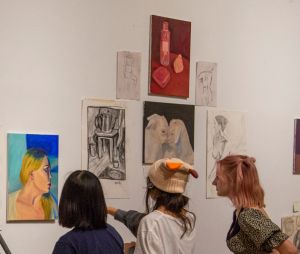 Three teenaged students examining the artwork of a peer