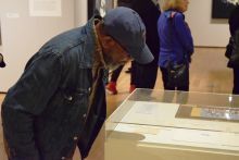 One person in a hat looking at an exhibit under glass