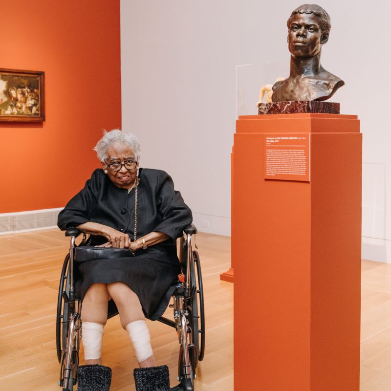 A person poses for a picture with a sculpture