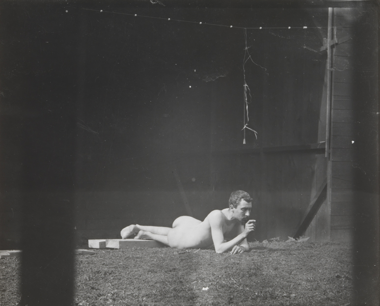 Male nude, lying on ground, in University of Pennsylvania photography shed