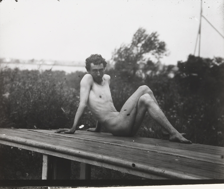 J. Laurie Wallace nude, semireclining on platform with water in background