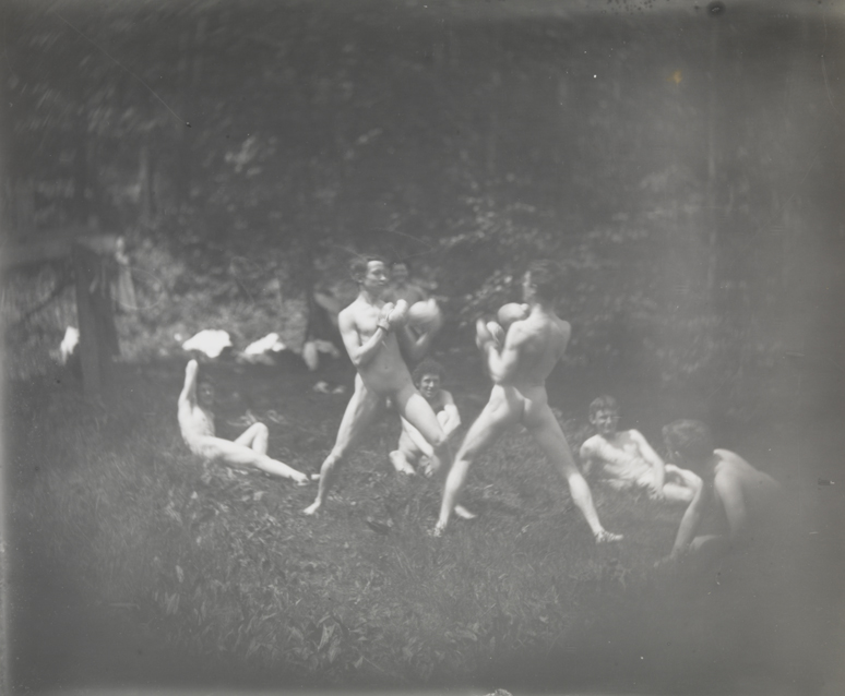 Seven males, nude, two boxing and three sitting behind