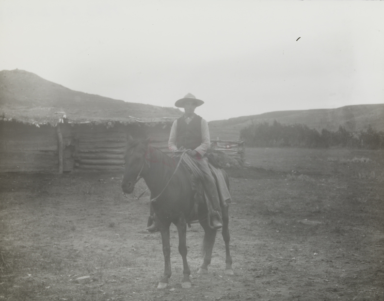 Cowboy in a dark vest, on dark horse