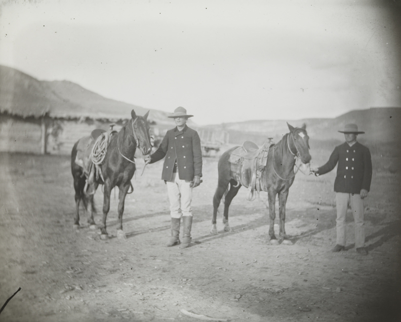 Two men standing with horses in BT Ranch yard