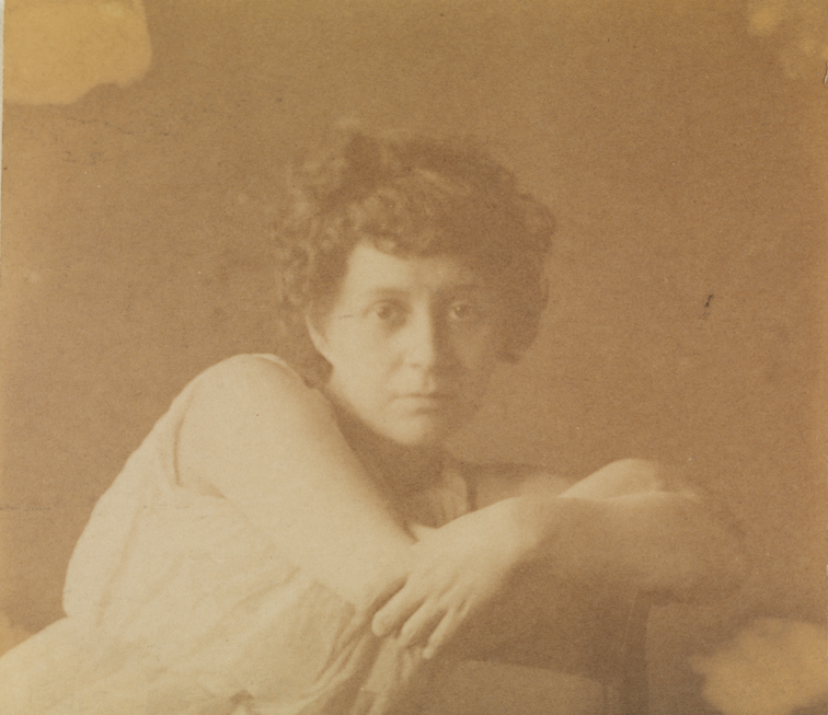 Woman in sleeveless dress, arms crossed over back of chair