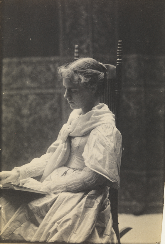 Eva Watson reading in high-backed chair