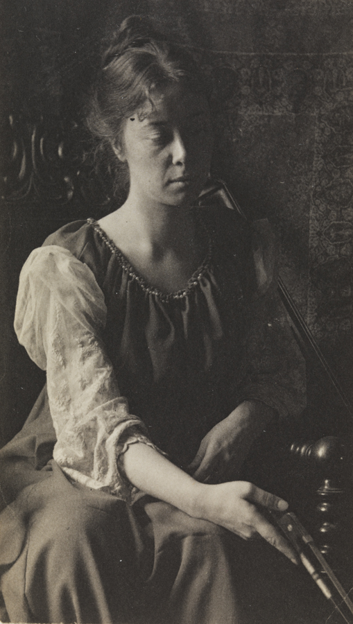 Clara Mather sitting in carved armcahir, holding cello bow