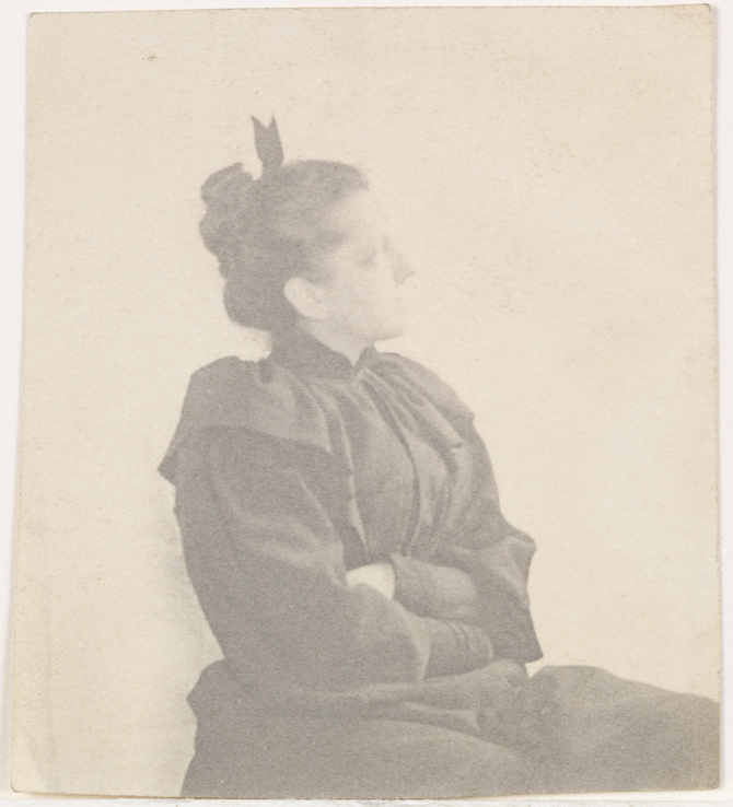 Inidentified woman sitting, facing right, arms folded