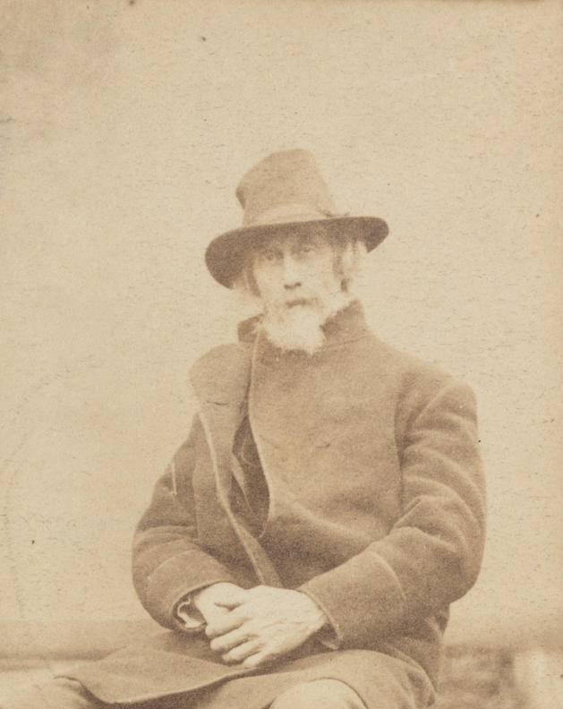 William H. Macdowell, in coat and hat, sitting