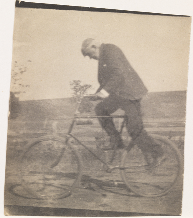 Benjamin Eakins riding bicycle, facing left