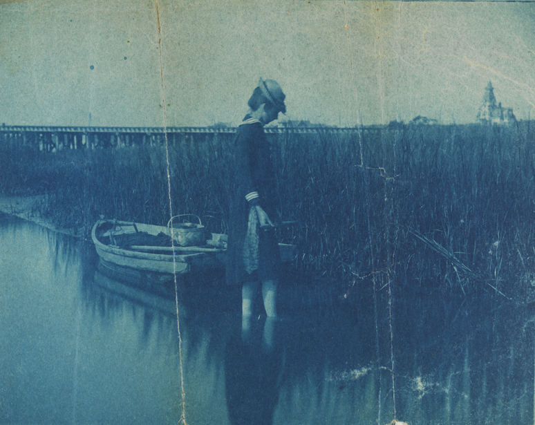 Young woman standing in water near rowboat