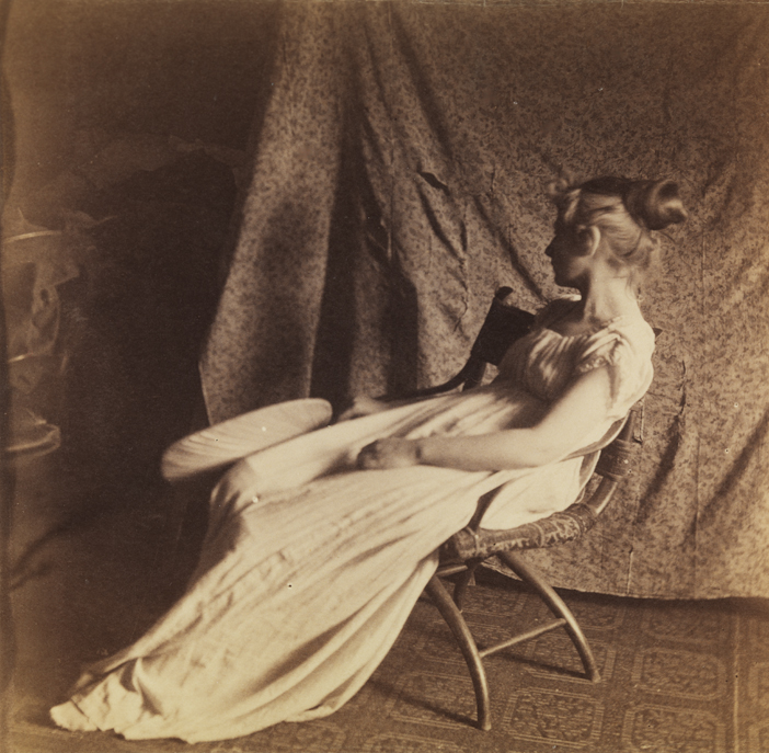 Woman sitting in bentwood chair, holding fan
