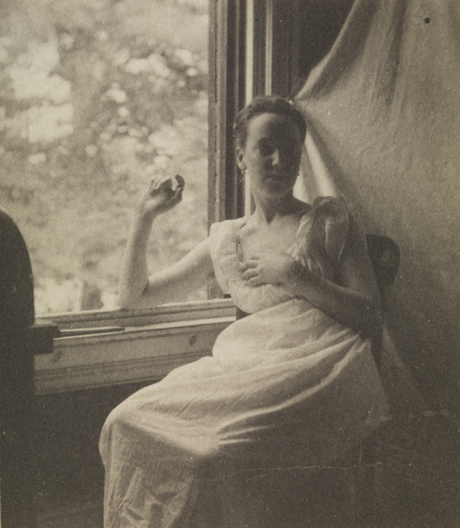 Woman sitting at open wondow, arm raised