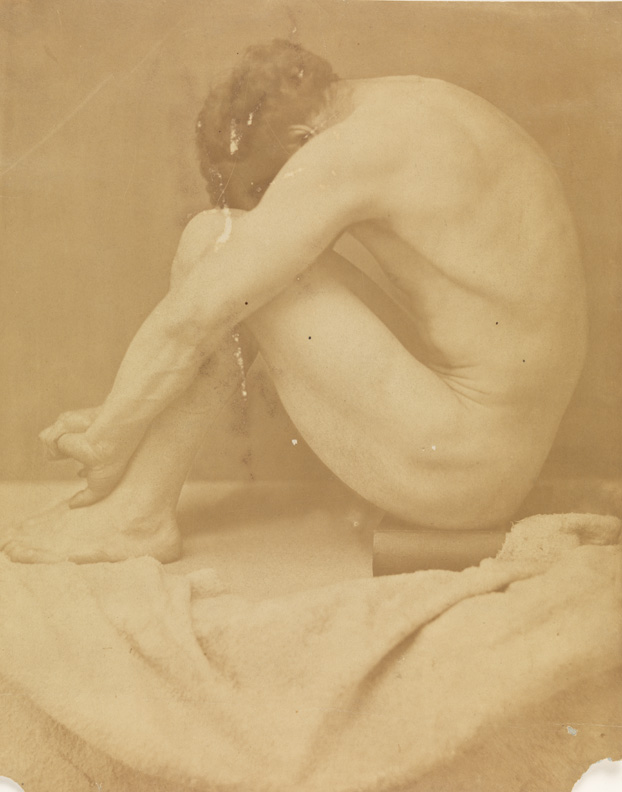 Male nude, sitting on book , head on knees