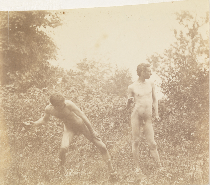 Male nude, poised to throw rock, and J. Laurie Wallace nude, looking right, in wooded landscape