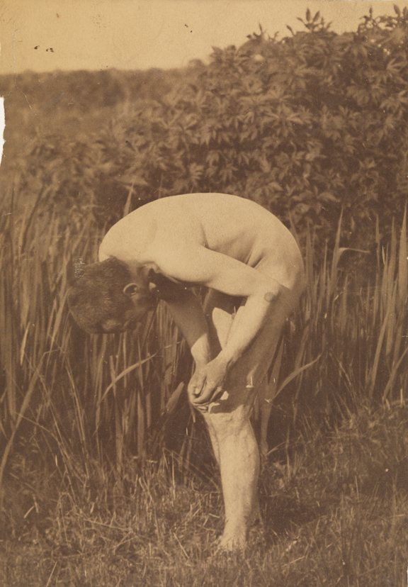 Thomas Eakins nude, bending forward, hand poised above left knee, in tall grass