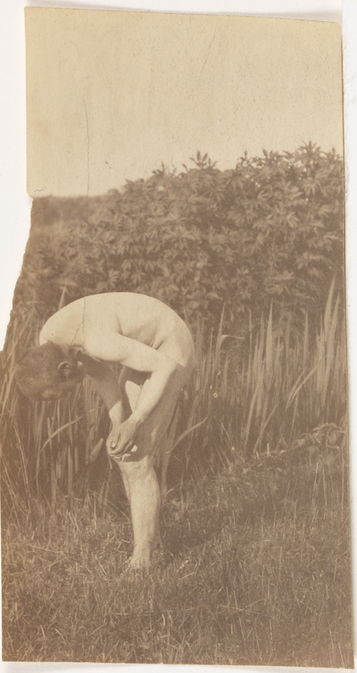 Thomas Eakins nude, bending forward, hands poised above left knee, in tall grass