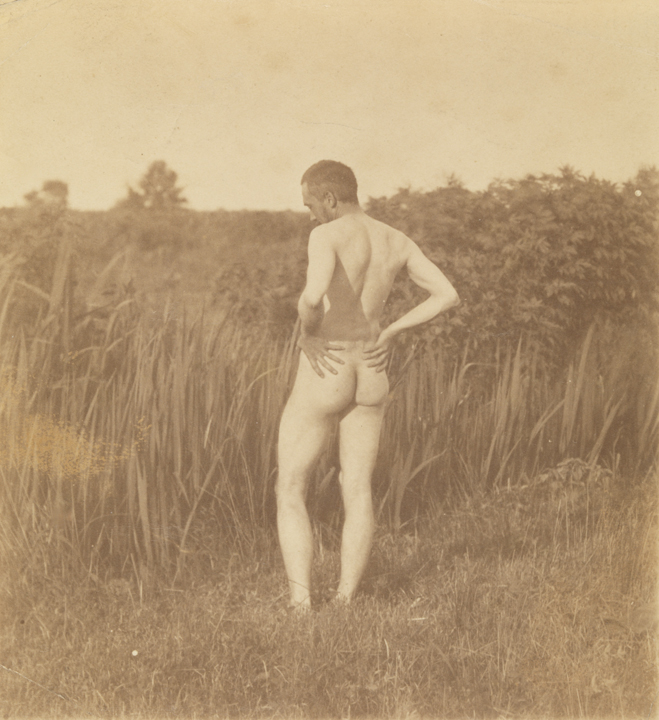 Thomas Eakins nude, hands on hips, from rear, in tall grass