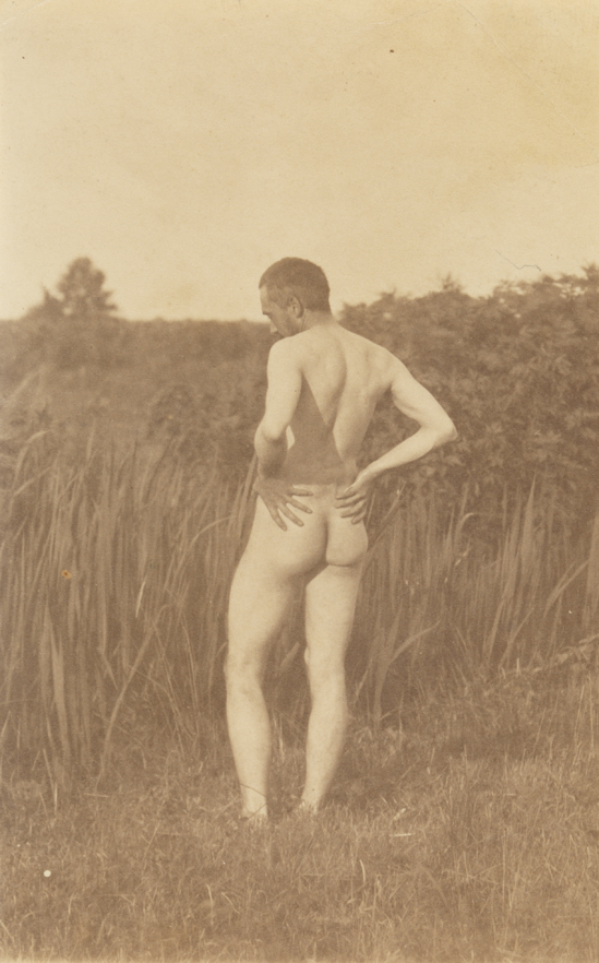 Thomas Eakins nude, hands on hips, from rear, in tall grass