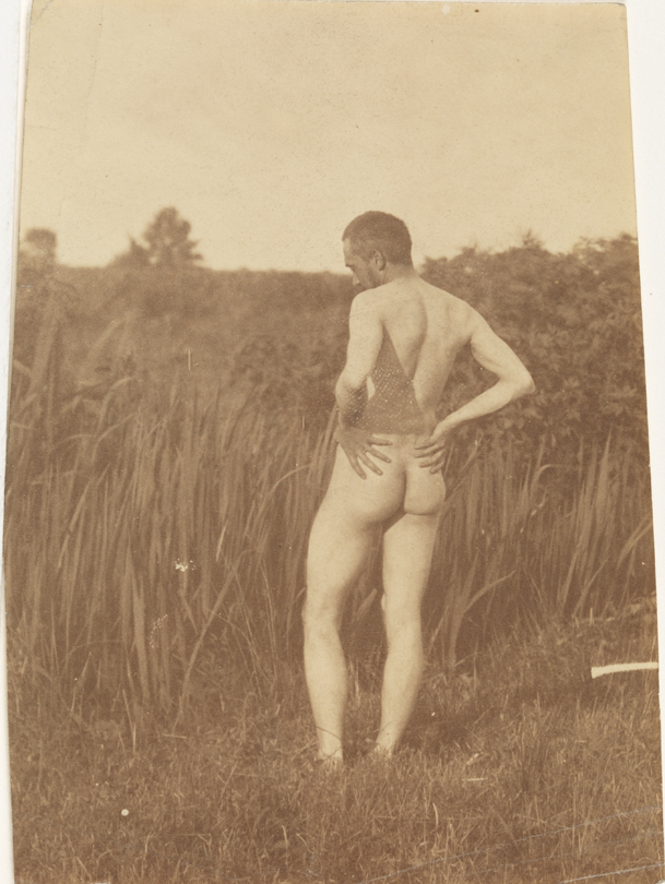 Thomas Eakins nude, hands on hips, from rear, in tall grass