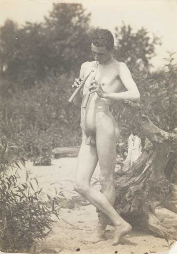 J. Laurie Wallace nude, playing pipes, facing left