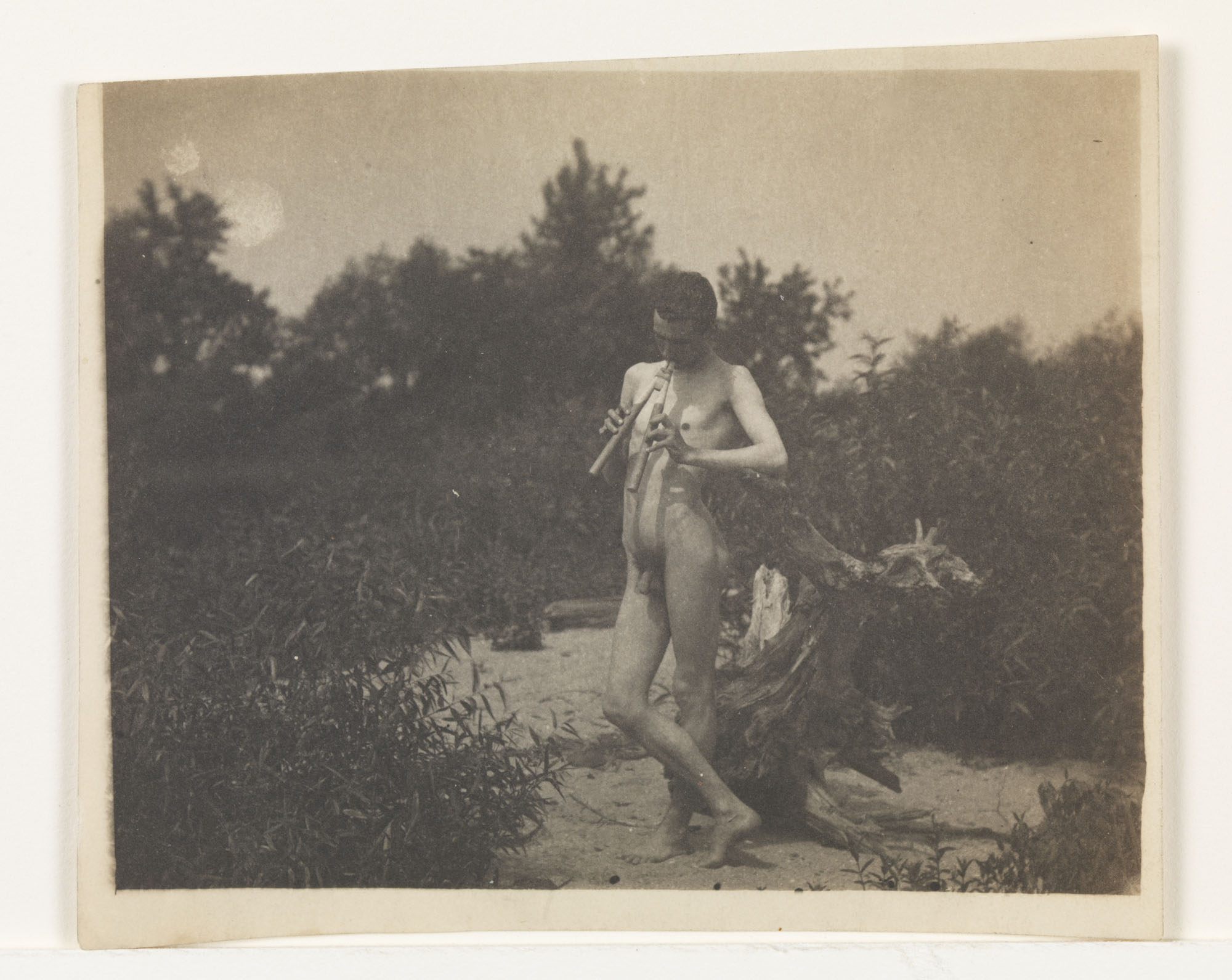 J. Laurie Wallace nude, playing pipes, facing left