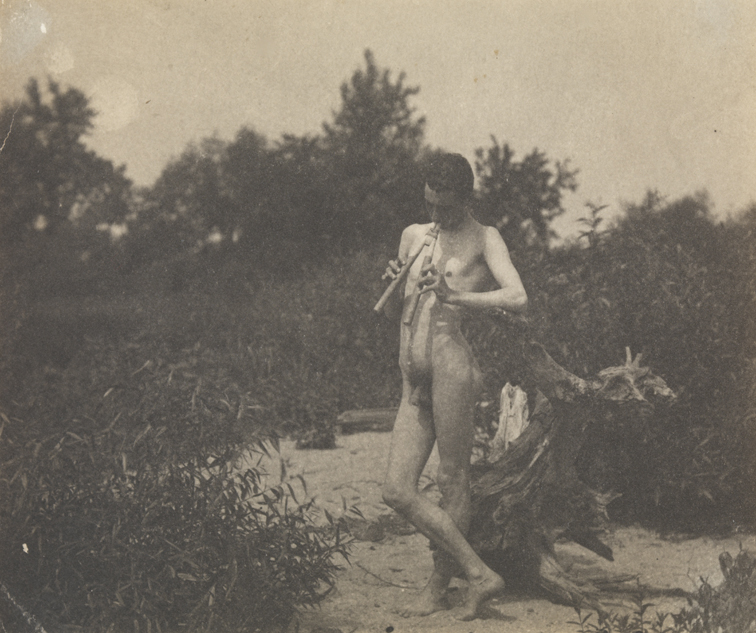 J. Laurie Wallace nude, playing pipes, facing left