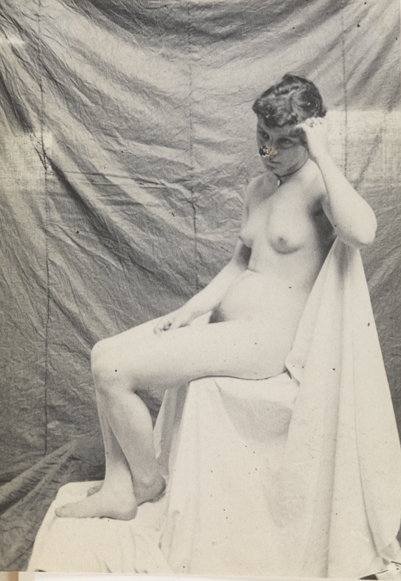 Female nude, seated on white draped chair, facing left