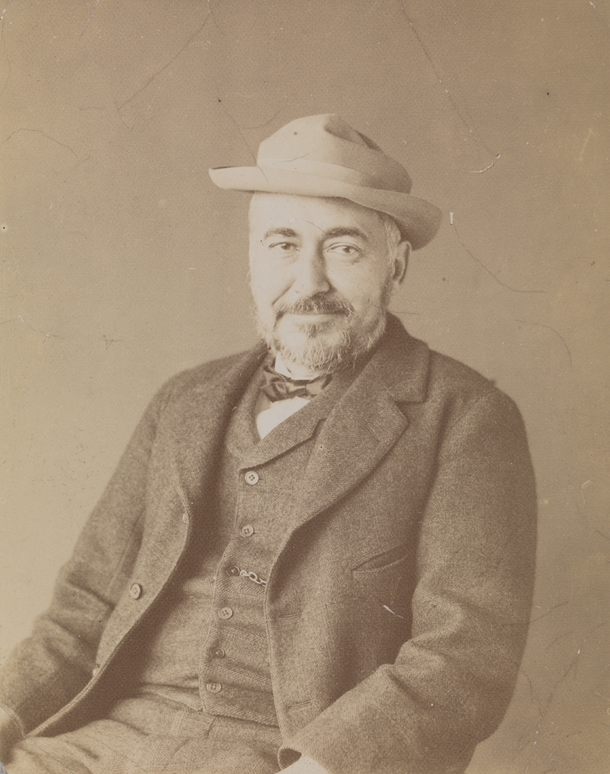 Thomas Eakins sitting, smiling, wearing hat