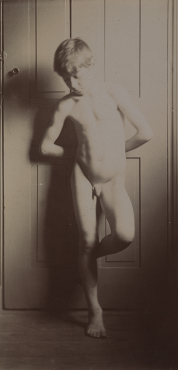 Boy nude, leaning against door