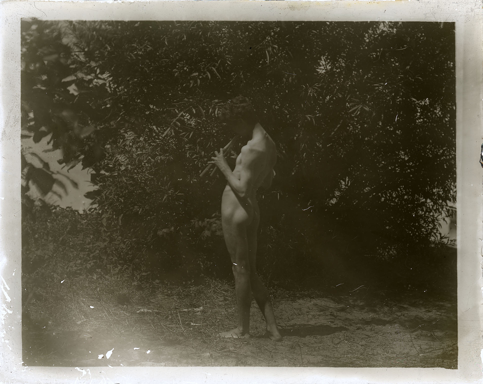 J. Laurie Wallace nude, playing pipes, facing left