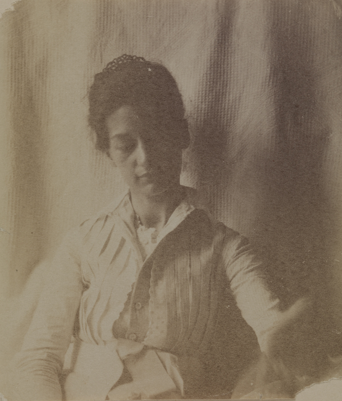 Mary Macdowell in light dress, sitting, looking down