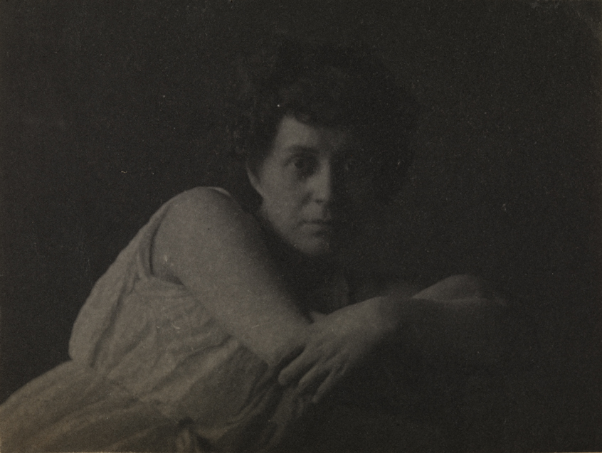 Cecil Boulton in sleeveless dress, arms crossed over back of chair