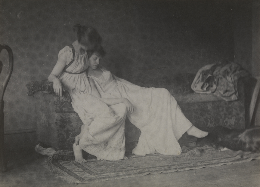 Two women in classical costume, sitting on couch