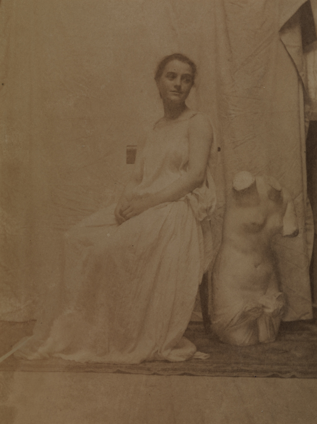 Katherine Cook (?) in classical costume, sitting next to Venus torso