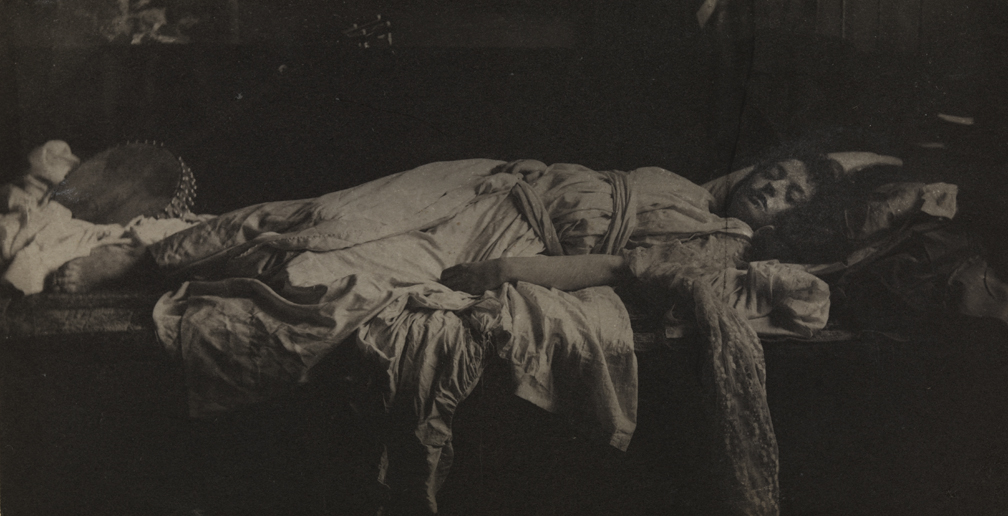 Blanche Gilroy in classical costume, reclining, with banjo