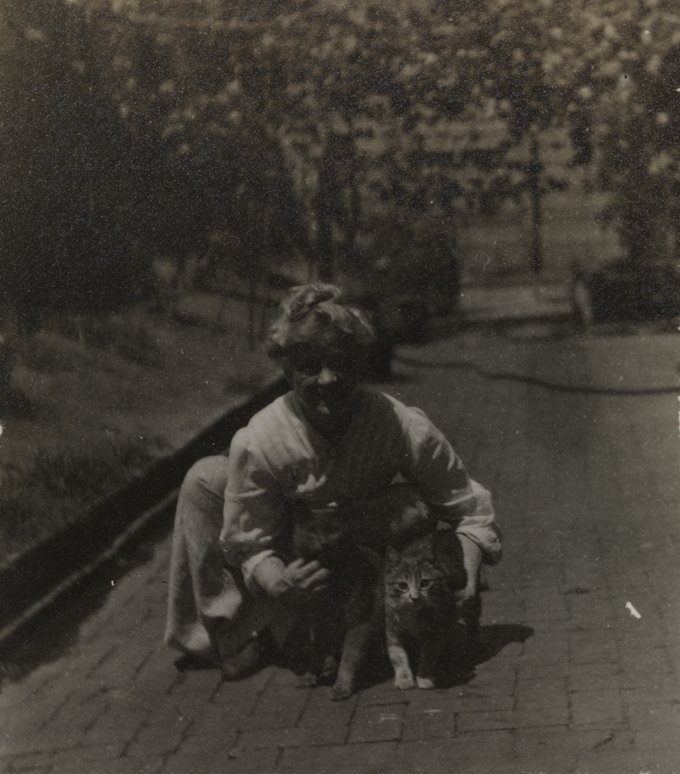 Susan Macdowell Eakins crouching with cats in yard of the family home at 1729 Mount Vernon Street, Philadelphia