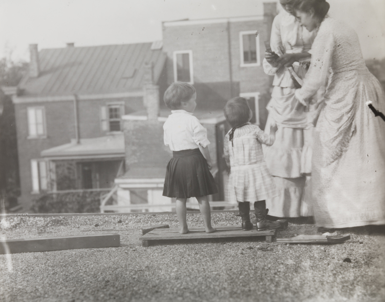 Two Crowell children, Margaret Eakins, and Frances Crowell, standing on roof