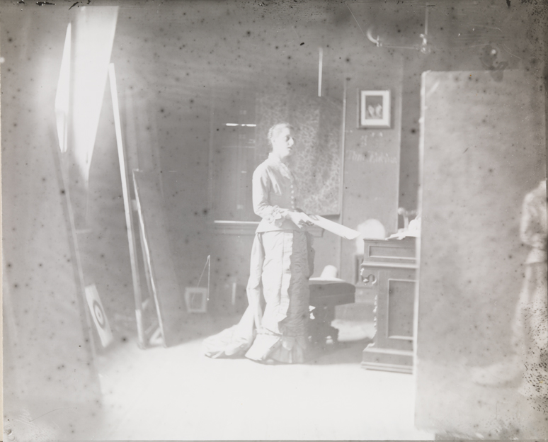 Margaret Harrison posing for "Singing a Pathetic Song", painting visible at right