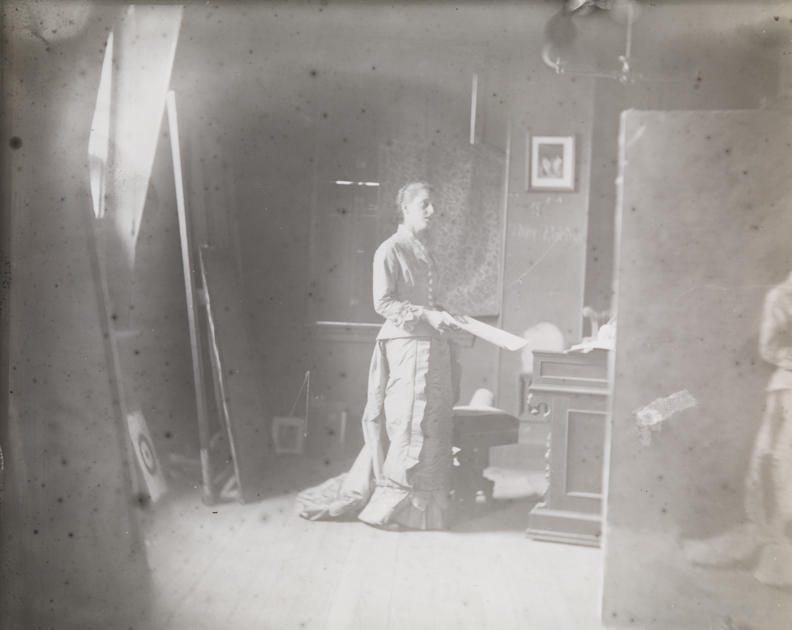 Margaret Harrison posing for "Singing a Pathetic Song," painting visible at right