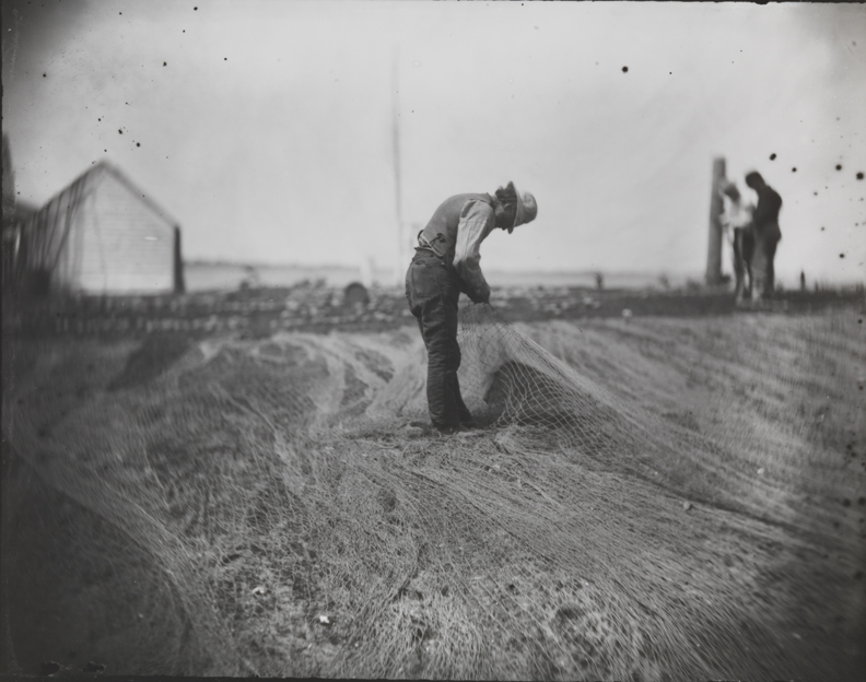 Three fishermen mending nets