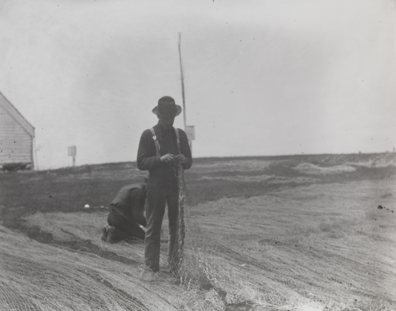 Two fishermen mending nets