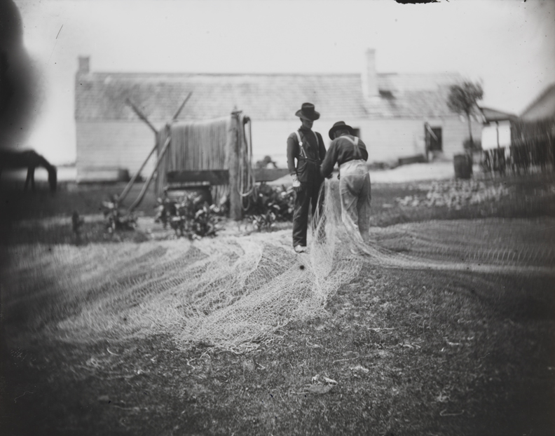 Two fishermen mending nets