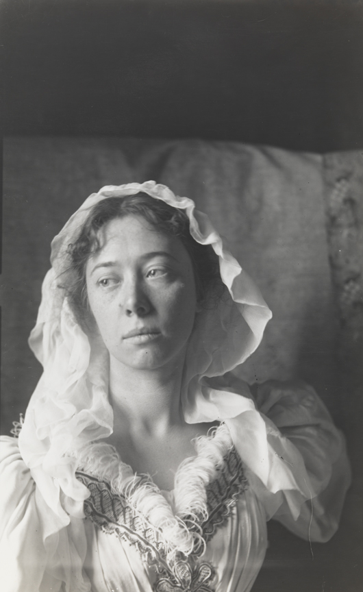 Clara Mather wearing head scarf and dress with feathered neckline