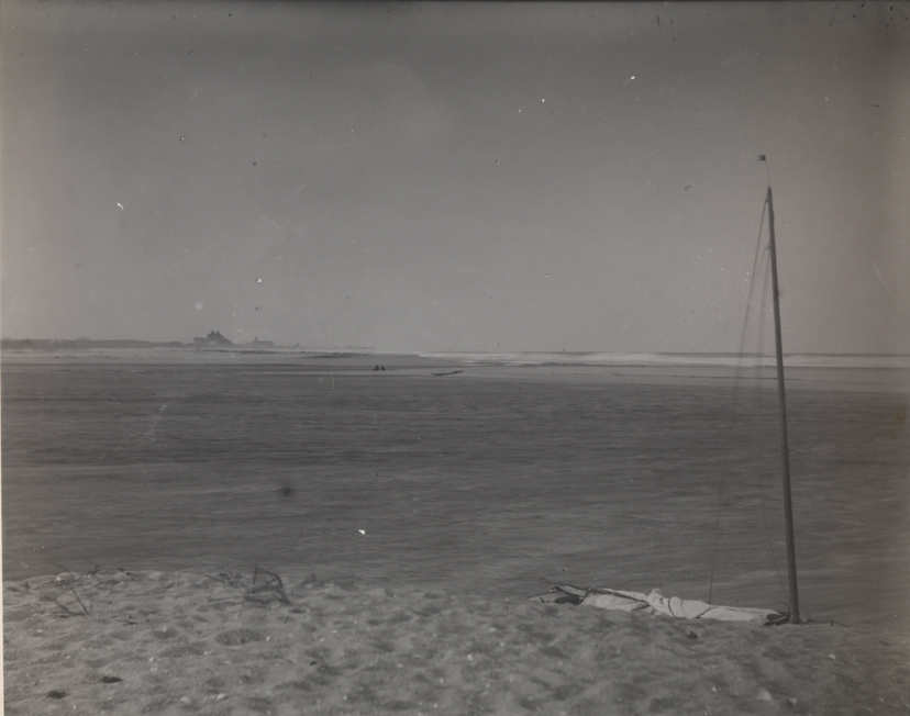 Beach with sailboat on sand and Beach House Hotel in distance, at Manasquan, New Jersey