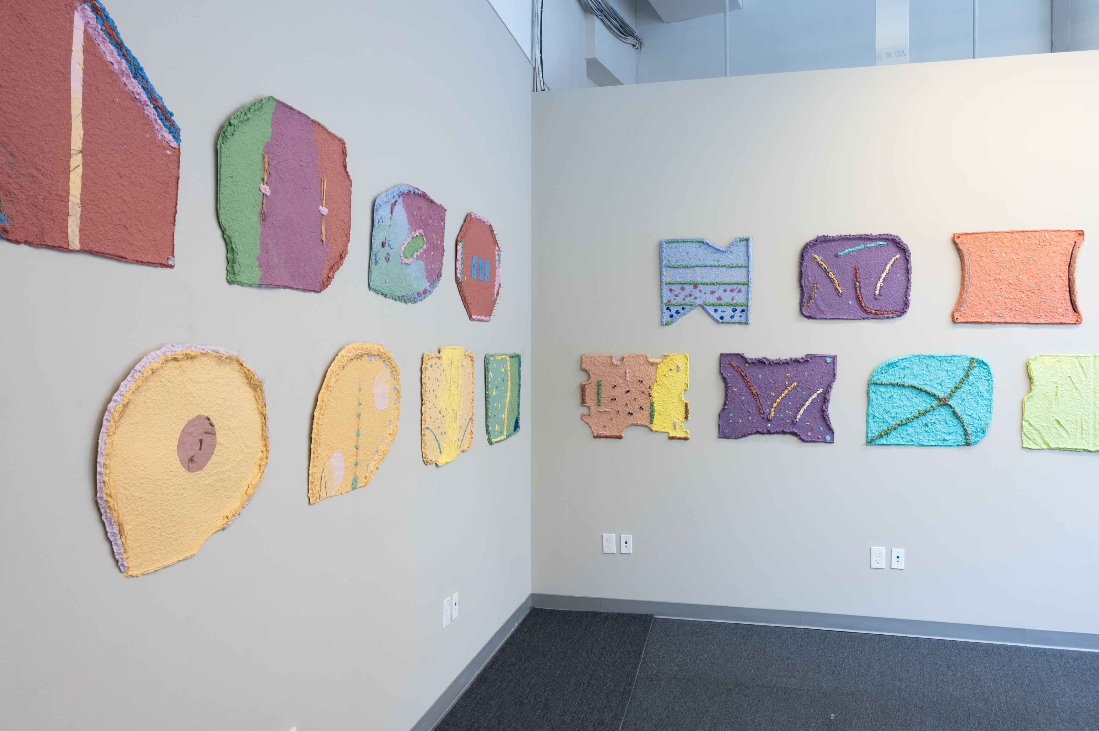 This image features textile art pieces by Teresa Baker, characterized by handmade paper and varied, colorful shapes.